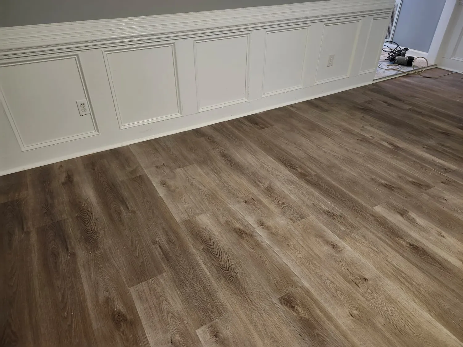 White wainscoting and trim above new plank flooring